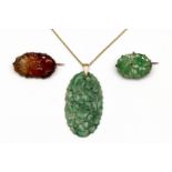 Gouden ovale hanger van gesneden jade met decor van bloemen.