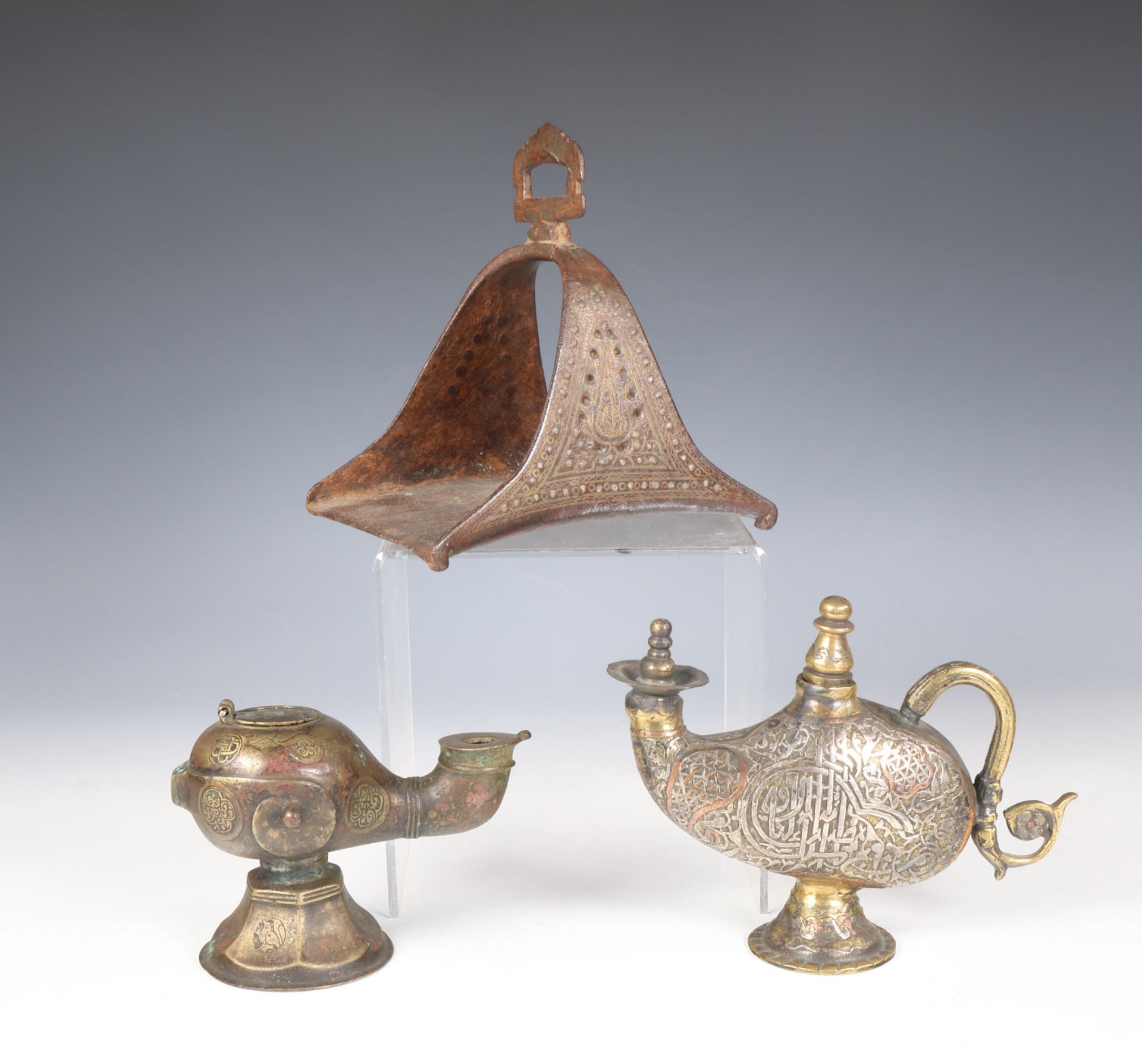 Iran, a metal horse shoe stirrup, a bronze oillamp and a bronze water sprinkler highlighted with sil