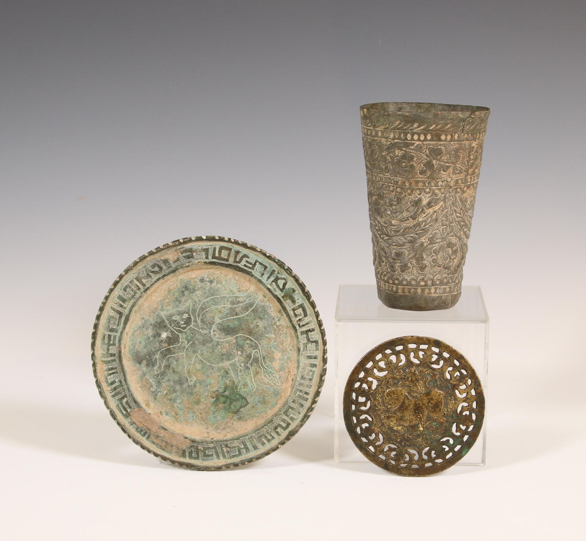Persia, a bronze round open worked panel, a bronze dish and a metal cup, 17th-19th century;