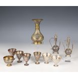 A collection of seven silver alloy cups, two metal niello miniature flasks with lids and a brass vas
