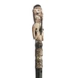 A bamboo flute with a carved figure on top