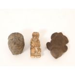 An antique stone figure of a tortois and a anthropomorph stone head.