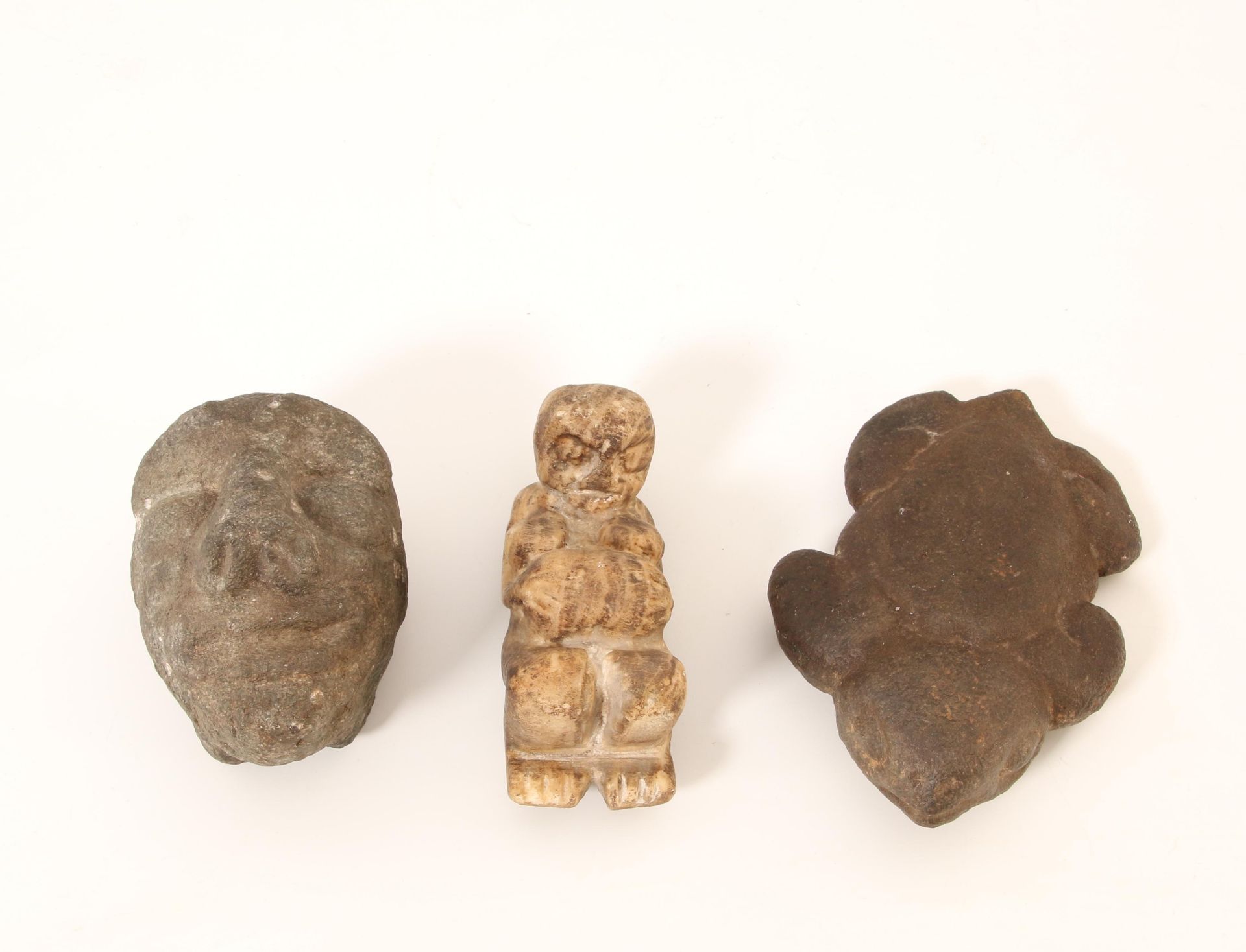 An antique stone figure of a tortois and a anthropomorph stone head.