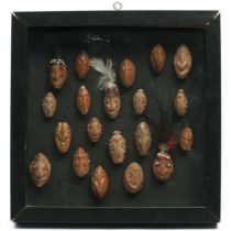 P.N. Guinea, Sepik, a collection of 20 miniature nutshell masks/ amulets within a frame.