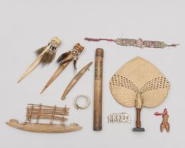 A collection of various ornamets and objects, among which an Asmat bamboo pipe, a model Massim canoe