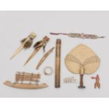 A collection of various ornamets and objects, among which an Asmat bamboo pipe, a model Massim canoe