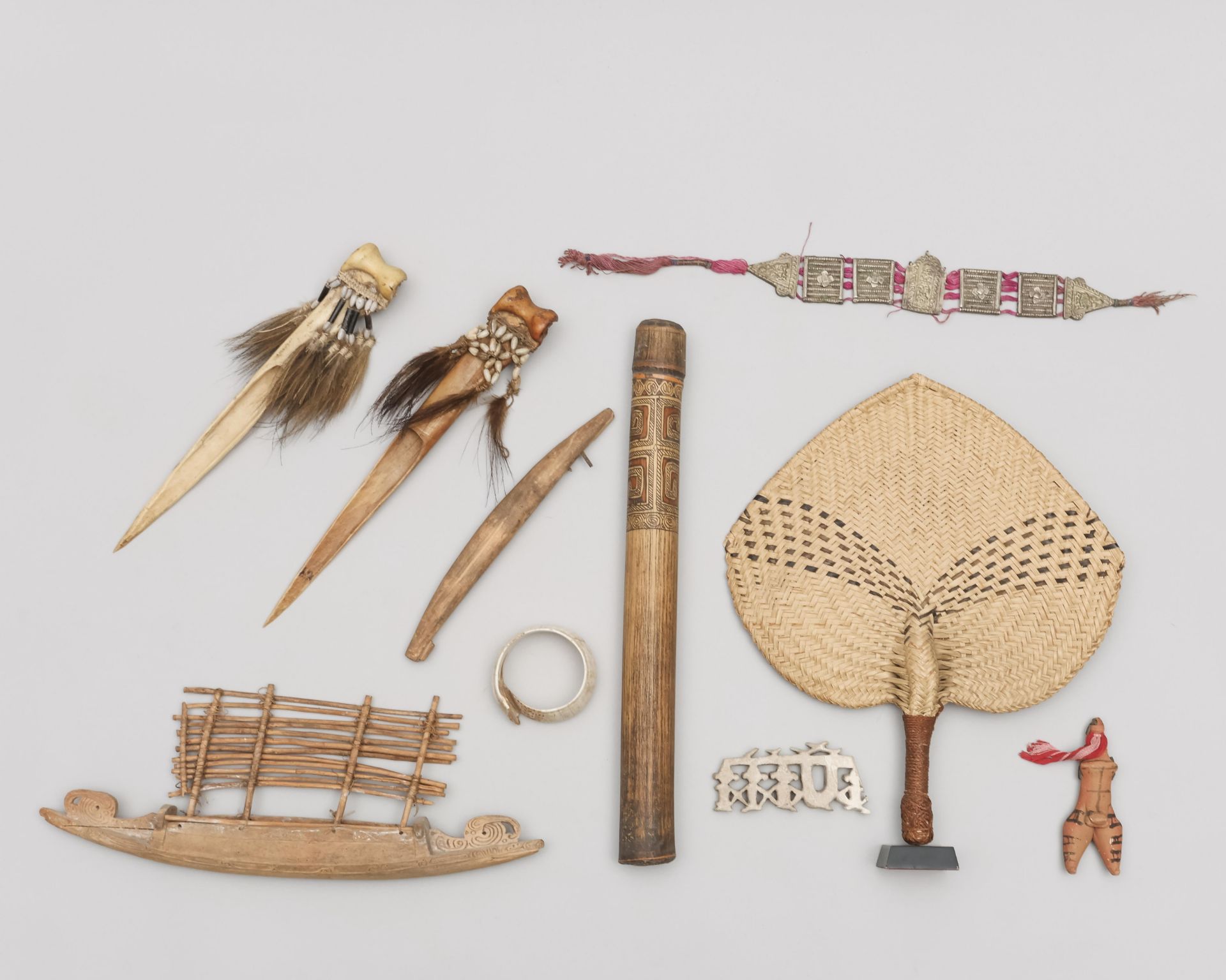 A collection of various ornamets and objects, among which an Asmat bamboo pipe, a model Massim canoe