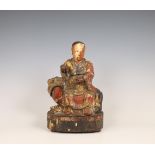 China, lacquered wood figure of a dignitary seated on a lion, 18th/ 19th century,