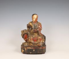 China, lacquered wood figure of a dignitary seated on a lion, 18th/ 19th century,