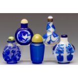 China, five blue overlay glass and blue glass snuff bottles and stoppers, 19th century,