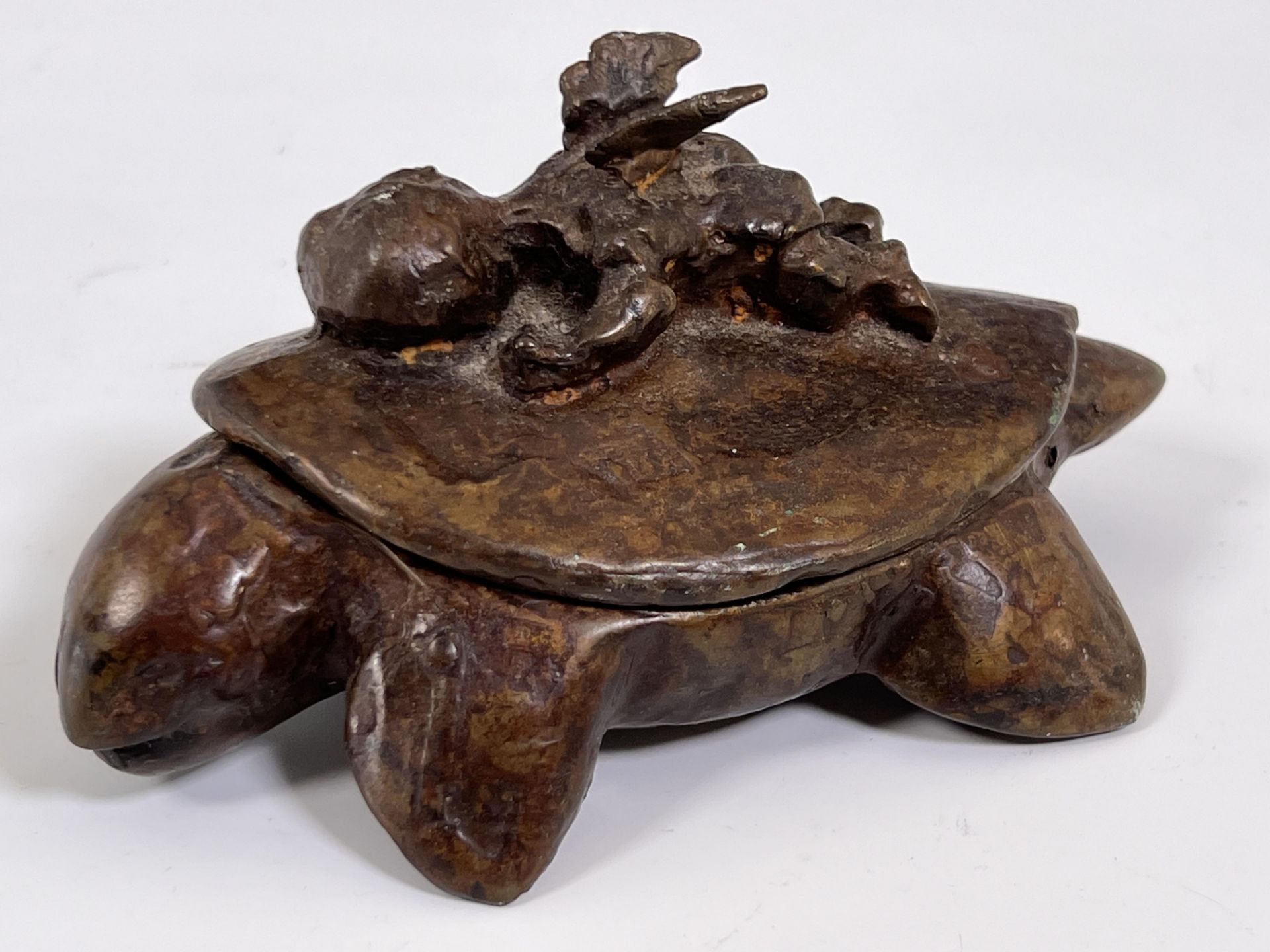 Een modern bronzen dekseldoos in de vorm van een schildpad met een liggende engel op schild