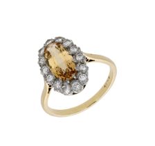 A topaz and diamond cluster ring, the oval mixed-cut topaz claw-set within a surround of bri...
