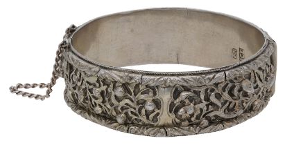 A 20th century Chinese silver bangle, the hinged bangle heavily chased with floral motifs an...