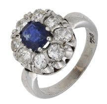 A sapphire and diamond cluster ring, the oval mixed-cut sapphire claw-set within a surround...