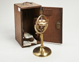 A VICTORIAN GRAVITATIONAL BRASS GYROSCOPE IN A MAHOGANY CASE. 23 cms high