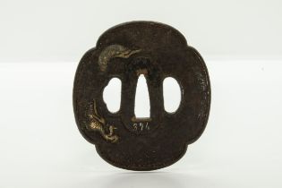 A JAPANESE IRON TSUBA decorated with a dragon ‘piercing’ the plane of the guard, a finely