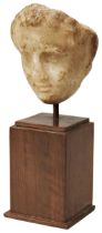 A ROMAN HEAD. Possibly a female deity but worn and fragmentary now mounted on a wooden base. 13cms