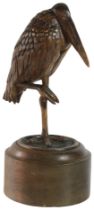 A contemporary carved walnut heron standing stark upon a circular oak base, (H: 33cm, W: 15cm)