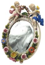 A CONTINENTAL PORCELAIN FRAMED TABLE MIRROR, 19TH CENTURY, the oval form mirror surmounted by twin