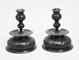 A PAIR OF REPOUSSE DWARF BRASS CANDLESTICKS DECORATED WITH SPOTS AND SPIRALS; HEAVILY PATINATED.