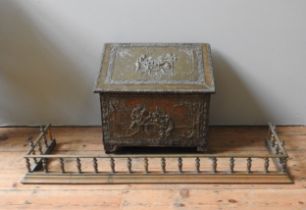 A BRASS COAL BOX AND FIRE CURB, the sloped cover coal box with embossed tavern scene decoration (
