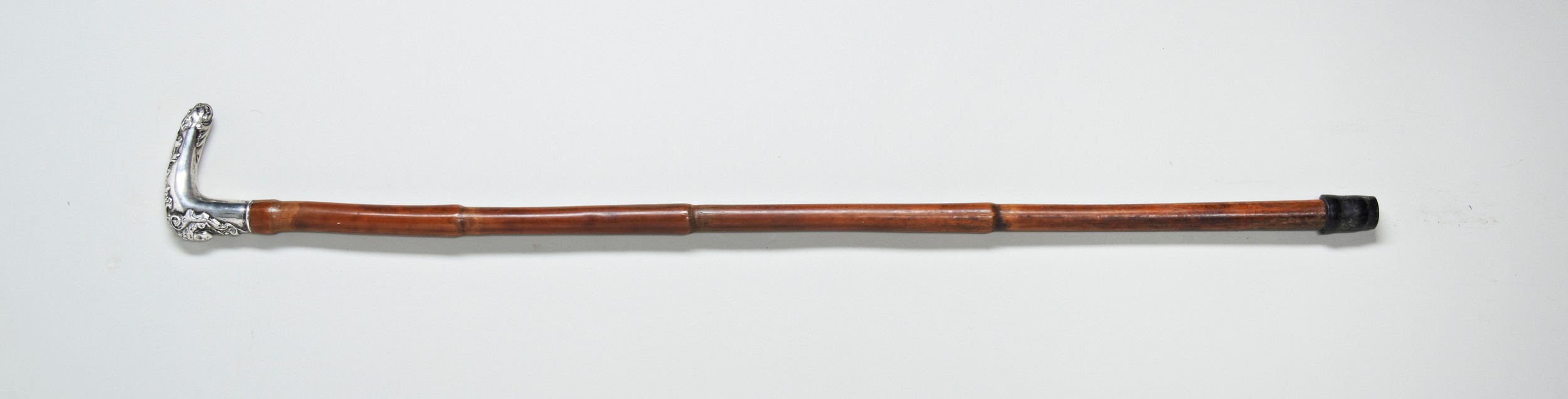 A 19TH CENTURY CANE with an ornate white metal handle decorated with a head of a grotesque and a