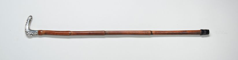 A 19TH CENTURY CANE with an ornate white metal handle decorated with a head of a grotesque and a