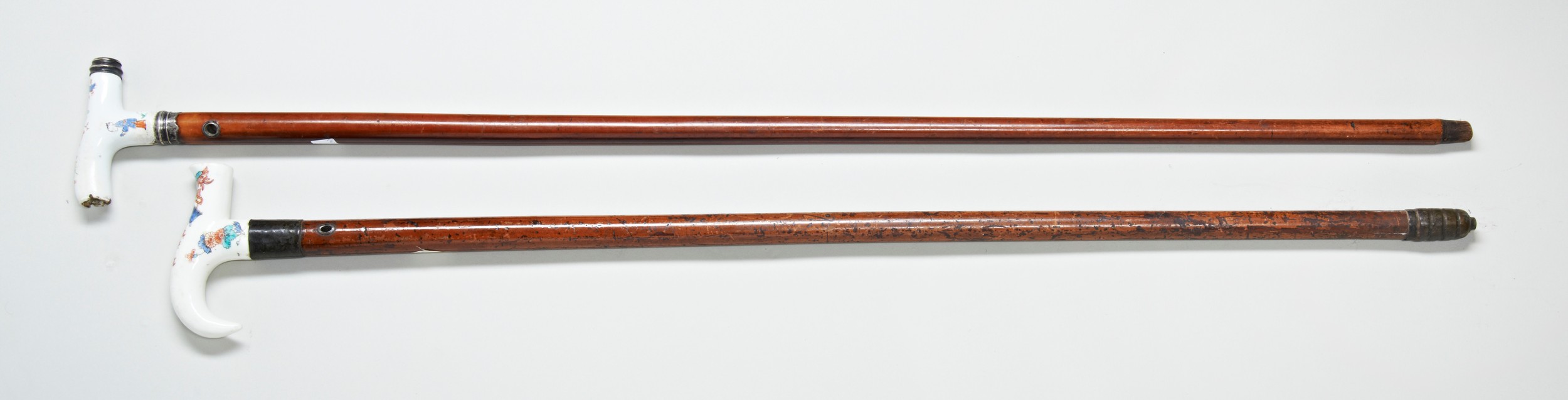 A 19TH CENTURY MALACCA CANE  with a Japanese porcelain handle and another similar. 90 cms max