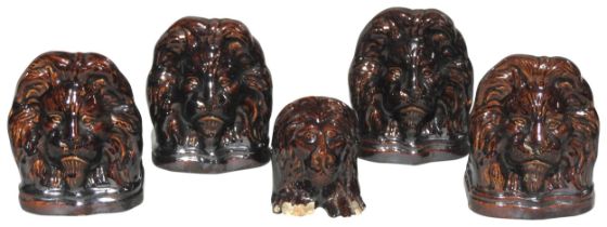 A GROUP OF FIVE EARLY 19TH CENTURY TREACLE GLAZE EARTHENWARE WINDOW STOPS, modelled as lions 14 cm