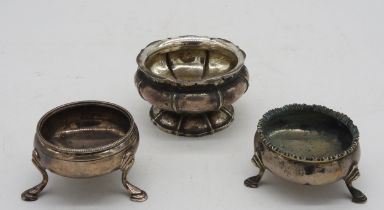 A GEORGE III SILVER SALT AND TWO OTHER GEORGIAN SALTS, the scroll edge salt raised on a circular