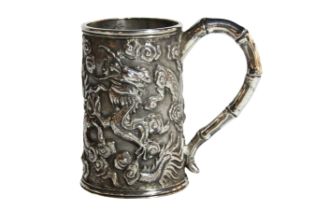 A small Chinese silver drinking vessel depicting dragons & mythical beasts with shaped handle, (H: 7