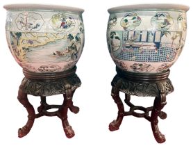 A huge pair of Chinese fish bowls with decorated panel scenes of traditional folk upon carved wooden