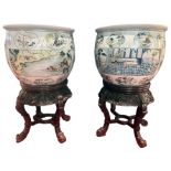 A huge pair of Chinese fish bowls with decorated panel scenes of traditional folk upon carved wooden