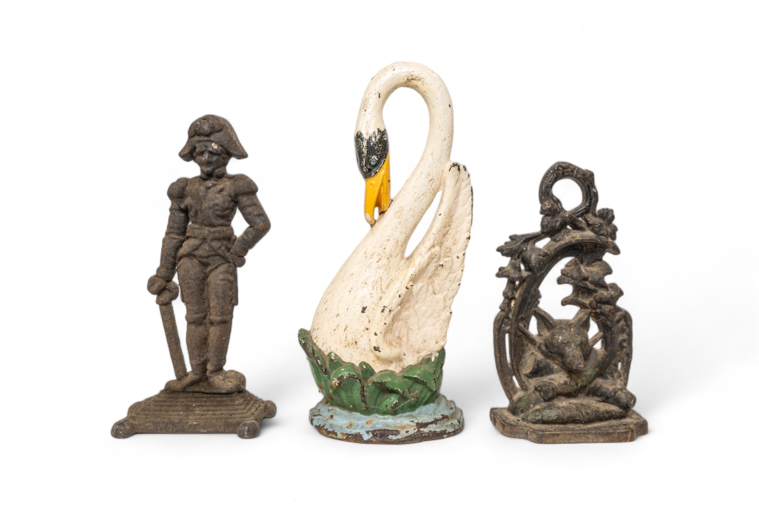 A CAST IRON DOORSTEP IN THE FORM OF A SWAN, another of a fox mask and another of a soldier. 40 cms