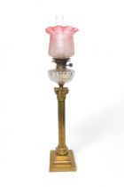A VICTORIAN OIL LAMP with a large brass Corinthian column reeded base, cut glass reservoir and