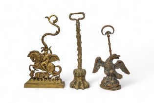 A BRASS LION'S PAW DOOR PORTER, an eagle brass door porter and another in the form of George and the