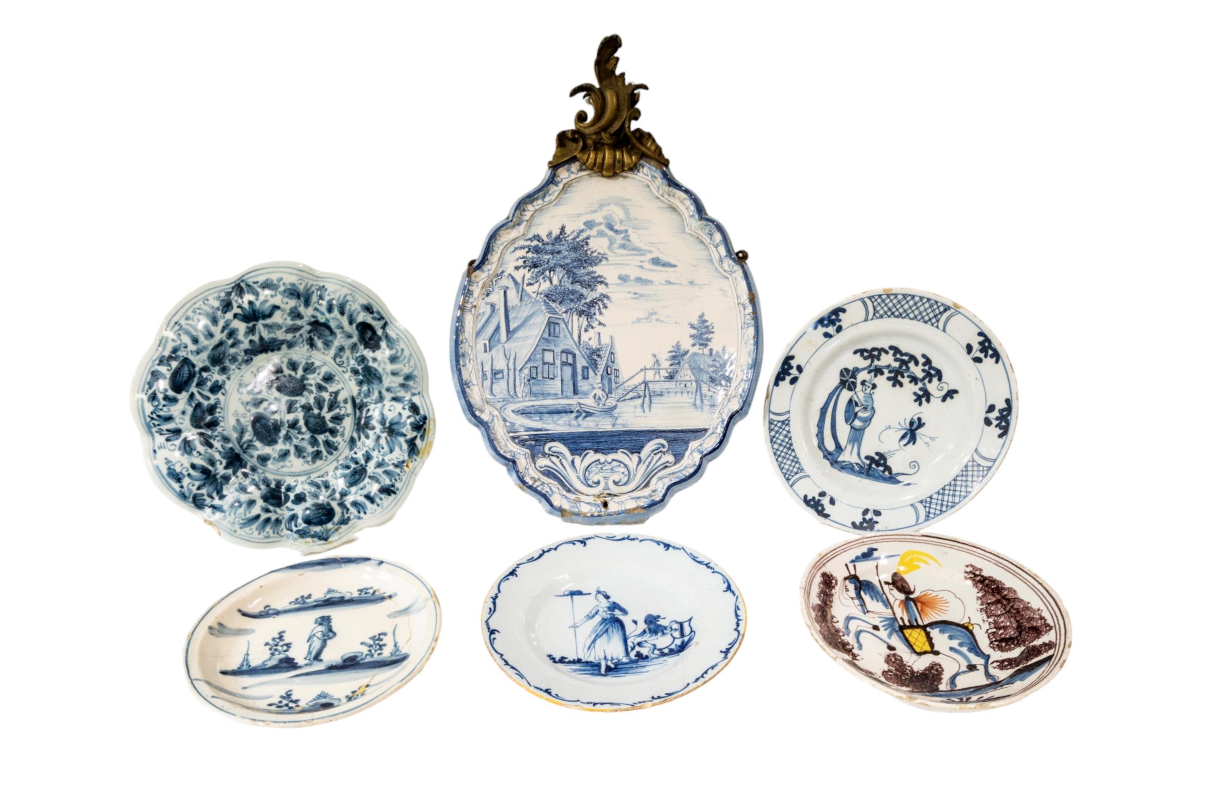 A DELFT MAKKUM CARTOUCHE FORM PANEL, hand painted with a bucolic river scene, surmounted by a gilt