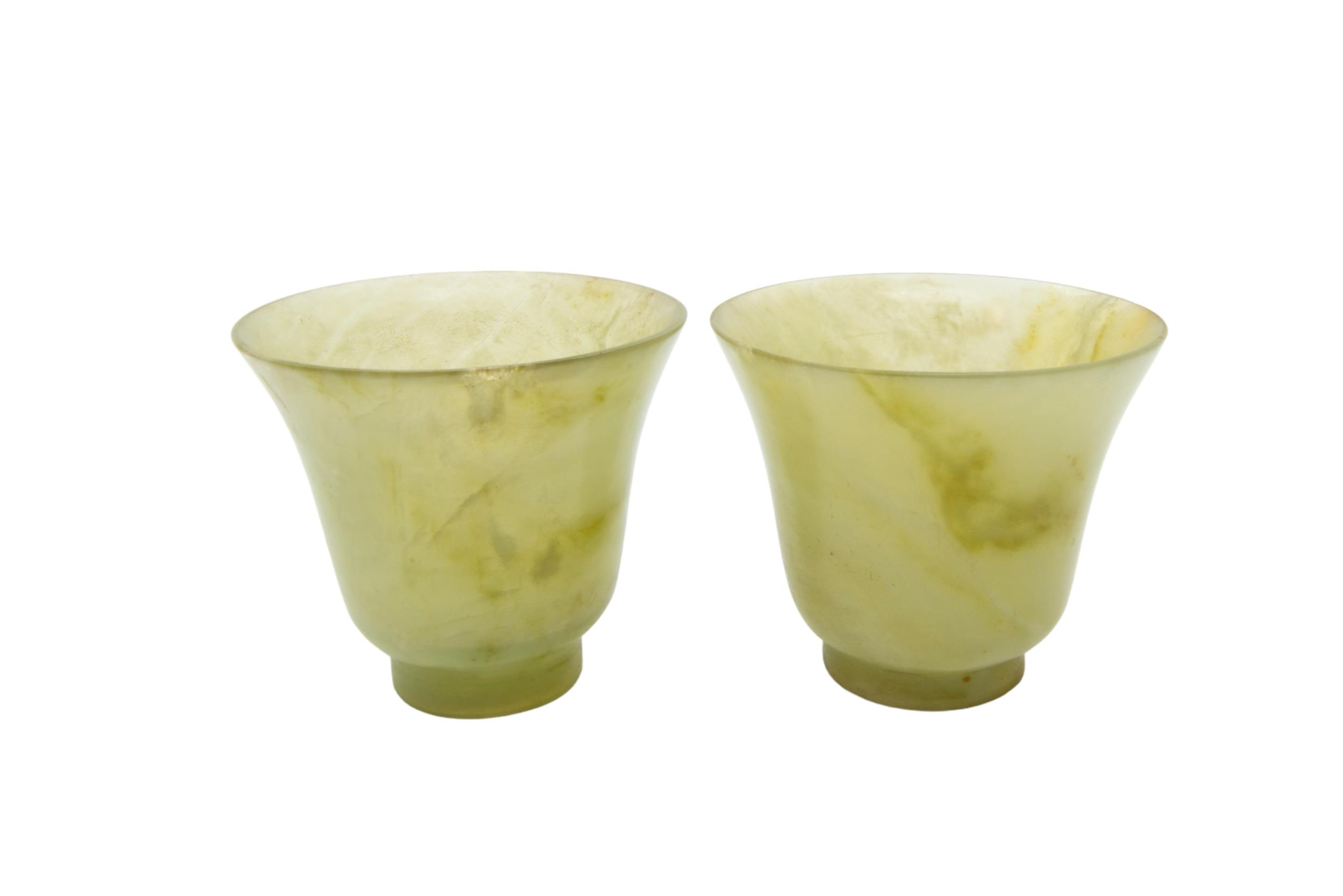 A FINE PAIR OF CHINESE CELADON AND RUSSETT JADE WINE CUPS 5 cm high x 6 cm diam