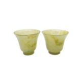 A FINE PAIR OF CHINESE CELADON AND RUSSETT JADE WINE CUPS 5 cm high x 6 cm diam