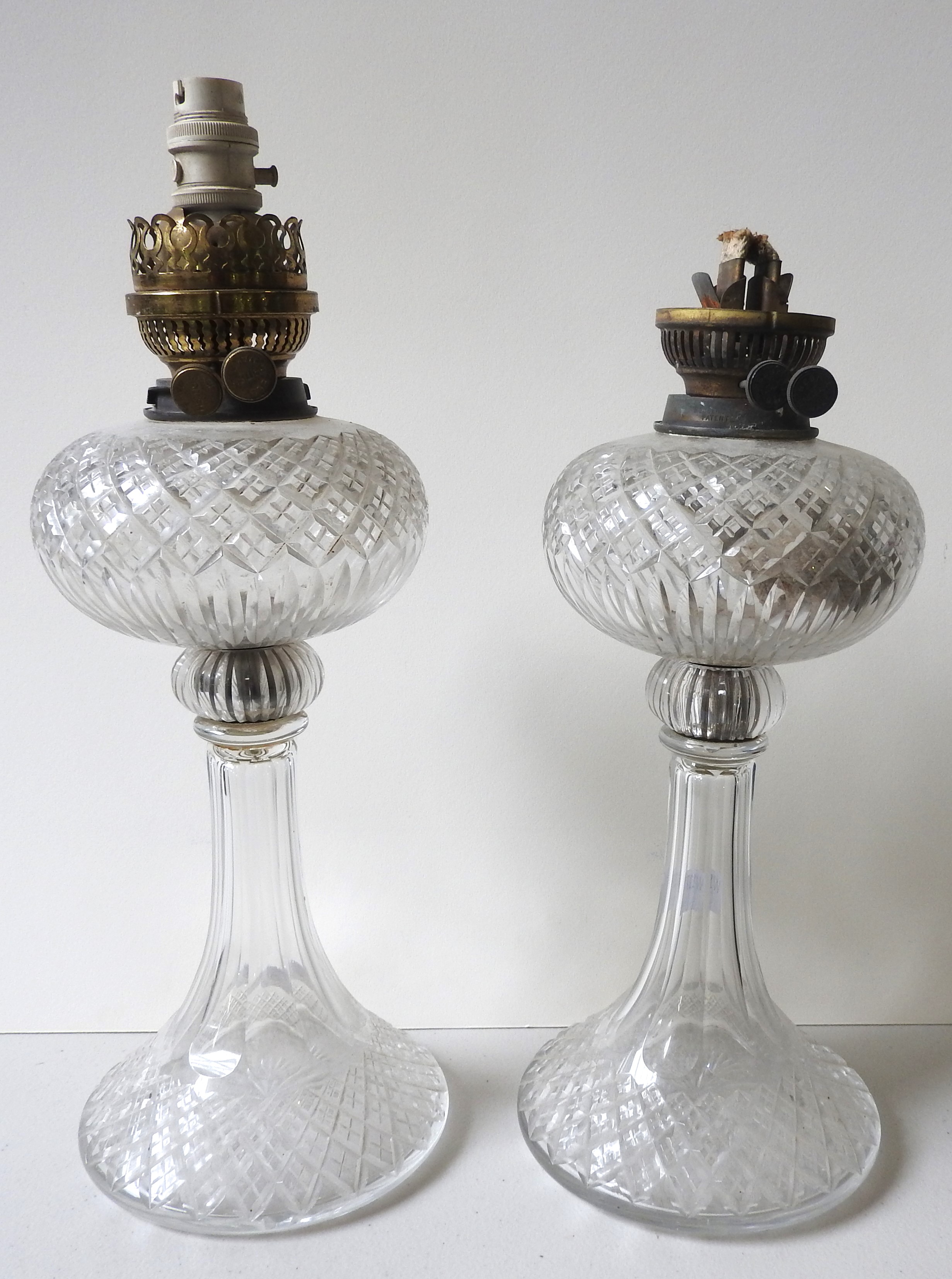 A PAIR OF CUT GLASS OIL LAMPS, early 20th century, with flared bases, the wick holders later changed