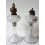 A PAIR OF CUT GLASS OIL LAMPS, early 20th century, with flared bases, the wick holders later changed
