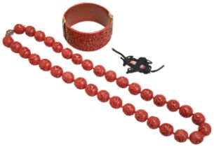 A CINNABAR LACQUER BEAD NECKLACE 20TH CENTURY together with A CINNABAR LACQUER BANGLE, EALRY 20TH