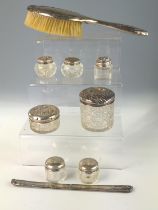 Silver backed hair brush, seven silver lidded glass vanity jars and a comb mount, various makers and