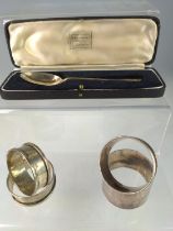 Four silver napkin rings, including a pair, and a cased teaspoon, various makers and dates, some ini