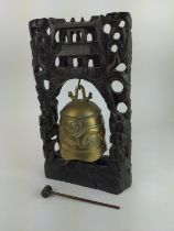 Eastern temple bell on carved wooden stand. 25cm x 38cm high.