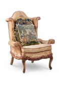 A CARVED WALNUT AND UPHOLSTERED WINGBACK ARMCHAIR IN 18TH CENTURY STYLE EARLY 20TH CENTURY