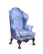 A MAHOGANY AND BLUE DAMASK UPHOLSTERED WING ARMCHAIR IN GEORGE II STYLE, LATE 19TH OR EARLY 20TH
