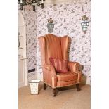 A CARVED WALNUT AND PINK STRIPE UPHOLSTERED WING ARMCHAIR IN 18TH CENTURY STYLE