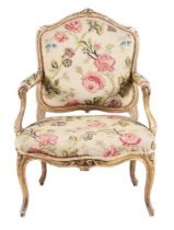 A CARVED GILTWOOD AND TAPESTRY UPHOLSTERED FAUTEUIL IN LOUIS XV STYLE