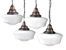 A SET OF FOUR 'CAPEL MAWR' PATINATED COPPER MOUNTED OPALINE GLASS PENDANT LIGHTS